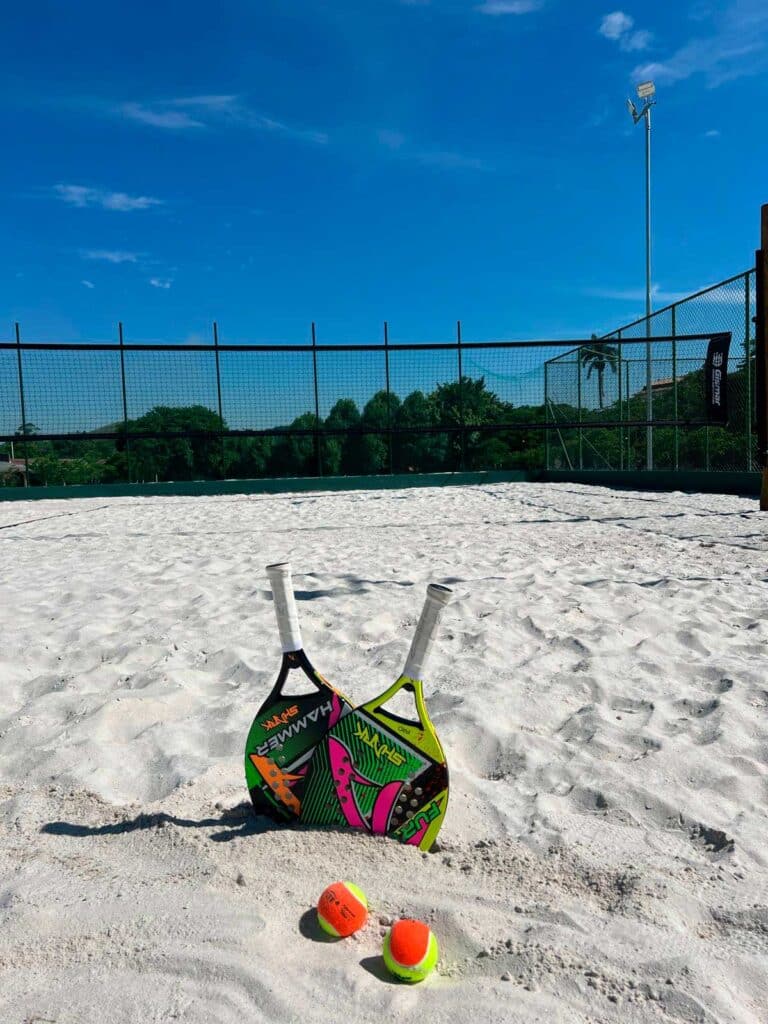 Raquetes e bolas de beach tennis sobre a areia da quadra