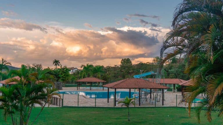 Piscinas e quiosques do Sabbia Club ao entardecer, com palmeiras