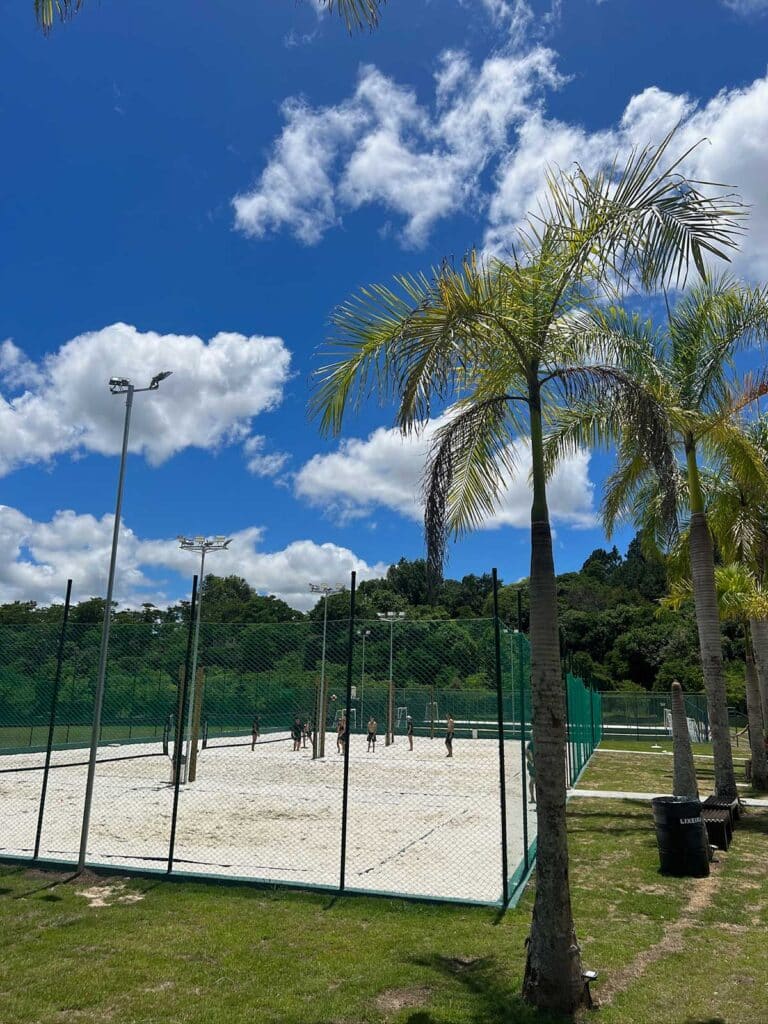 Quadras de areia do Sabbia Club com postes de iluminação e palmeiras