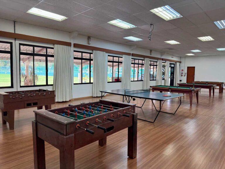Salão de jogos com mesas de tênis de mesa, pebolim e sinuca
