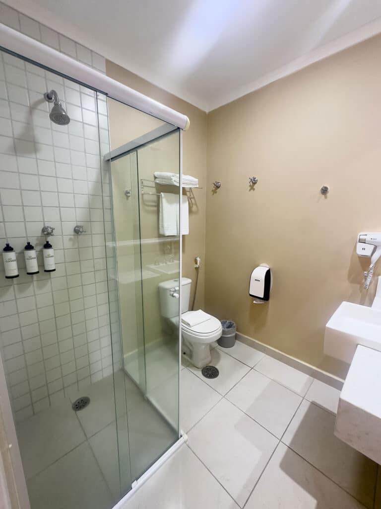 Banheiro privativo com box de vidro, ducha e amenities