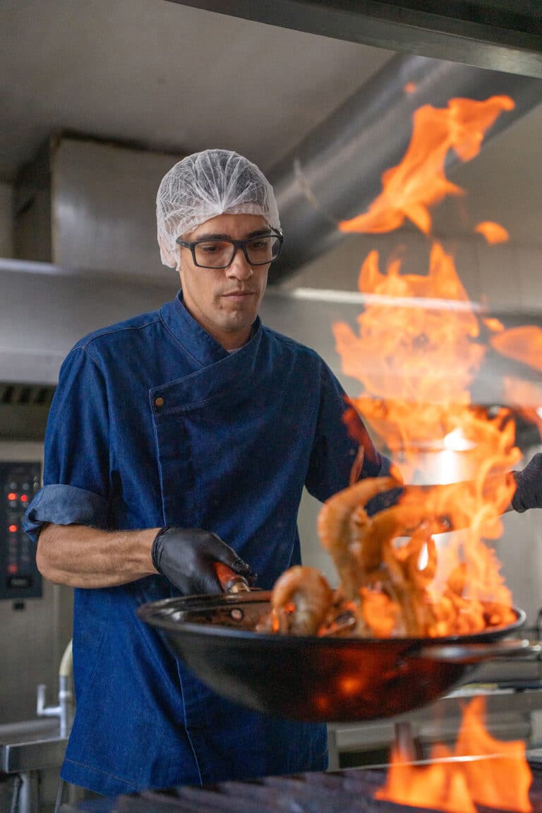 Cozinheiro flambando camarão em frigideira